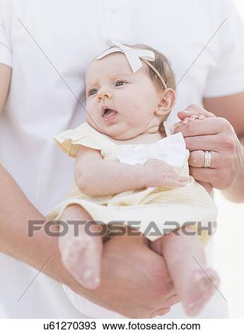 Stock Image - Studio shot portrait of baby girl (2-5 months) with father. Fotosearch