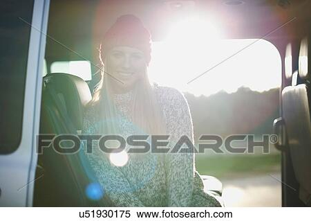 Stock Photography - Sunlit portrait of young woman sitting in back of car. Fotosearch