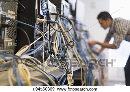 Stock Photo - Tangled cables with young technician man in background. Fotosearch