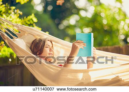 Teenage boy relaxing in garden hammock reading a book View Large Photo Image Stock Photo - Teenage boy relaxing in garden hammock reading a book. Fotosearch