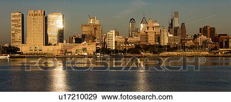 Stock Photo - The skyscrapers of Philadelphia rise above the Delaware River at sunrise. Fotosearch