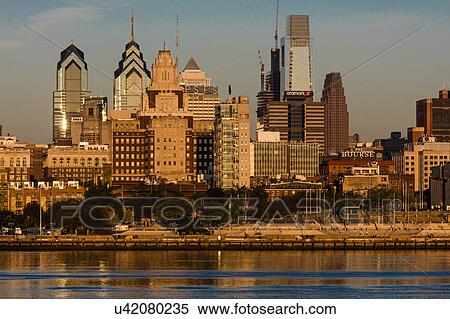 Stock Photography - The skyscrapers of Philadelphia rise above the Delaware River at sunrise. Fotosearch