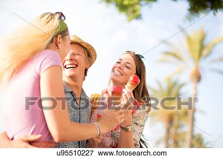Three adult friends laughing and eating ice cream cones, Majorca, Spain View Large Photo Image Stock Photo - Three adult friends laughing and eating ice cream cones, Majorca, Spain. Fotosearch