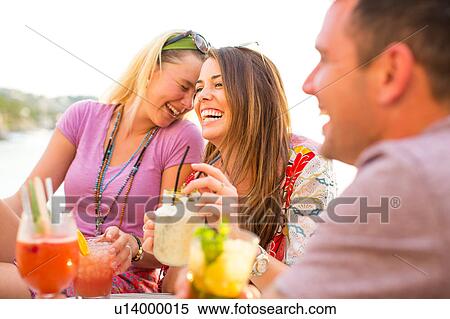 Three adult friends laughing over cocktails at waterfront restaurant, Majorca, Spain View Large Photo Image Stock Photography - Three adult friends laughing over cocktails at waterfront restaurant, Majorca, Spain. Fotosearch