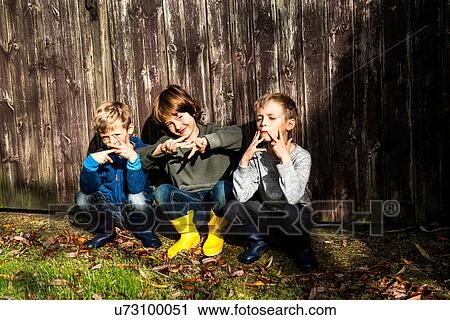 Three boys, outdoors, crouching beside fence, making hand gestures View Large Photo Image Stock Image - Three boys, outdoors, crouching beside fence, making hand gestures. Fotosearch