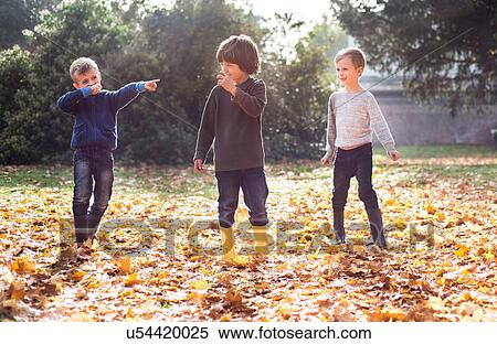 Three boys playing outdoors, in autumn leaves View Large Photo Image Stock Photography - Three boys playing outdoors, in autumn leaves. Fotosearch