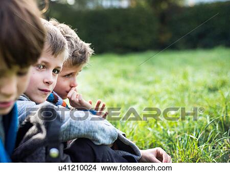 Picture - Three boys, sitting together in field, in autumn. Fotosearch