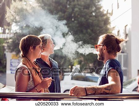 Three friends taking a cigarette break on sidewalk, Cape Town, South Africa View Large Photo Image Stock Image - Three friends taking a cigarette break on sidewalk, Cape Town, South Africa. Fotosearch
