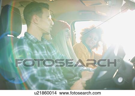 Picture - Three young adult friends driving in sunlit car. Fotosearch