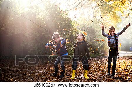 Stock Photo - Three young boys, playing outdoors, throwing autumn leaves. Fotosearch