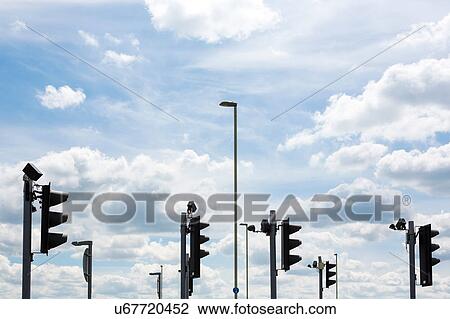 Stock Image - Traffic lights amongst street lamps and road signs, Swindon, Wiltshire, United Kingdom. Fotosearch