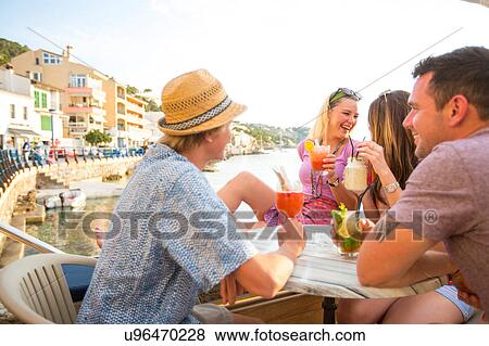 Two adult couples sharing cocktails at waterfront restaurant, Majorca, Spain View Large Photo Image Stock Photo - Two adult couples sharing cocktails at waterfront restaurant, Majorca, Spain. Fotosearch