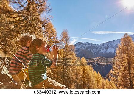 Two boys sitting on rocks, drinking from water bottles, Schnalstal, South Tyrol, Italy View Large Photo Image Stock Image - Two boys sitting on rocks, drinking from water bottles, Schnalstal, South Tyrol, Italy. Fotosearch