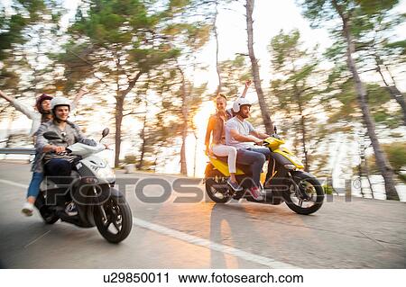 Stock Image - Two couples riding mopeds along coastal road, Split, Dalmatia, Croatia. Fotosearch
