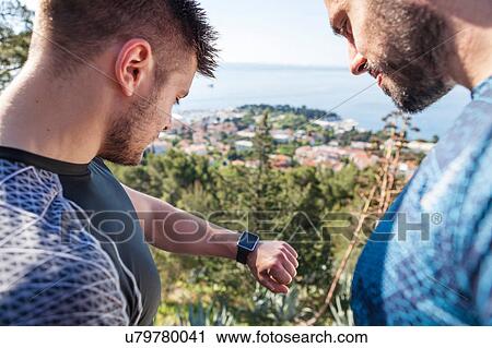 Stock Image - Two male runners checking smartwatch in park, Split, Dalmatia, Croatia. Fotosearch