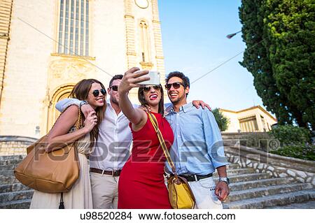 Picture - Two tourist couples taking selfie in front of church, Calvia, Majorca, Spain. Fotosearch