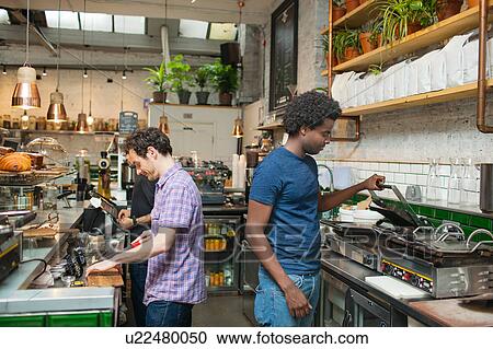 Stock Image - Two waiters preparing food in cafe kitchen. Fotosearch