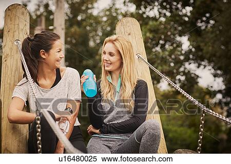 Stock Photography - Two women taking a training break in park. Fotosearch