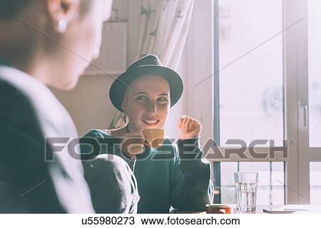 Stock Image - Two young female friends drinking espresso in kitchen. Fotosearch