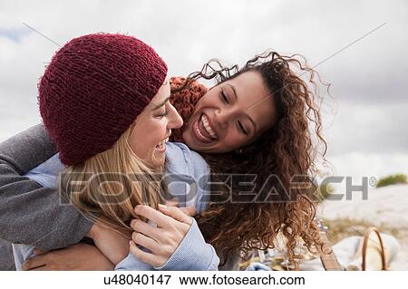 Stock Photo - Two young female friends hugging at beach, Western Cape, South Africa. Fotosearch