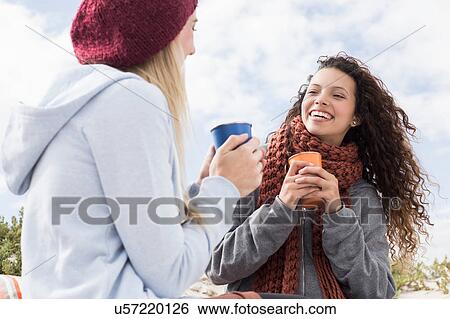 Stock Photograph - Two young women laughing at beach picnic, Western Cape, South Africa. Fotosearch