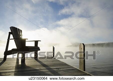 Picture - USA, New York, Chair on pier during sunrise. Fotosearch