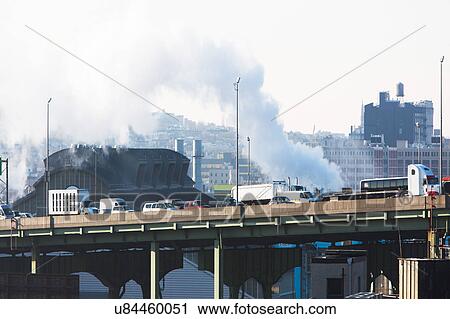 Stock Image - USA, New York, New York City, Smoke over bridge. Fotosearch