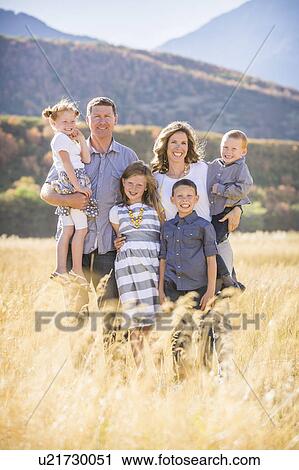 Stock Image - USA, Utah, Provo, Family with three children (4-5, 6-7, 8-9) standing in field. Fotosearch