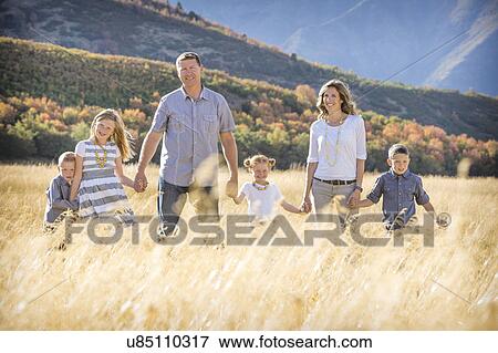 Stock Photo - USA, Utah, Provo, Family with three children (4-5, 6-7, 8-9) standing in field. Fotosearch