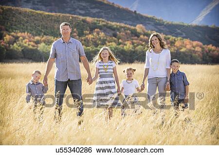 Stock Photograph - USA, Utah, Provo, Family with three children (4-5, 6-7, 8-9) standing in field. Fotosearch