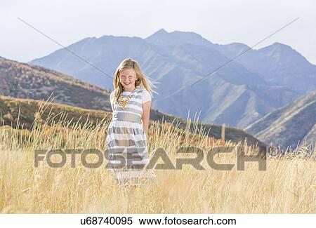 Stock Photography - USA, Utah, Provo, Girl (8-9) standing in field. Fotosearch