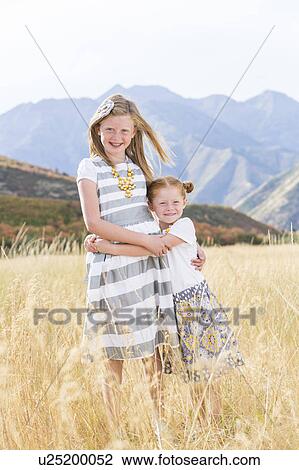 Stock Image - USA, Utah, Provo, Two girls (4-5, 8-9) standing in field. Fotosearch