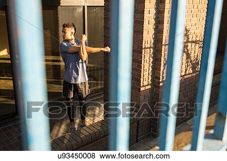 View through bars of man stretching beside column View Large Photo Image Stock Photo - View through bars of man stretching beside column. Fotosearch