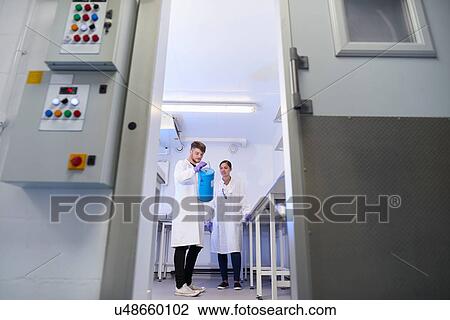 Stock Image - View through doorway of scientists in laboratory. Fotosearch