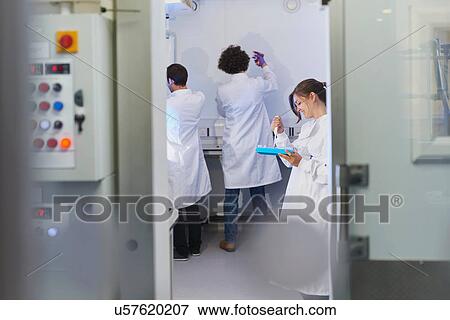 Stock Photo - View through doorway of scientists in laboratory. Fotosearch