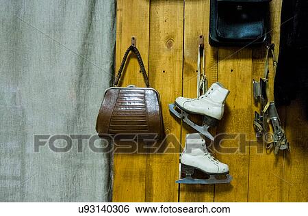 Stock Photograph - Vintage ice skates and handbag hanging from wooden wall. Fotosearch