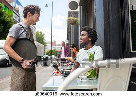 Waiter serving young man at city sidewalk cafe View Large Photo Image Stock Photograph - Waiter serving young man at city sidewalk cafe. Fotosearch