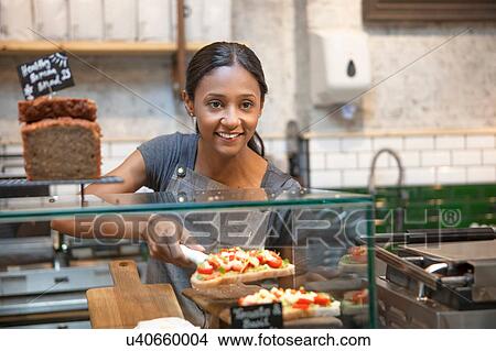 Picture - Waitress serving open sandwich from cafe display cabinet. Fotosearch