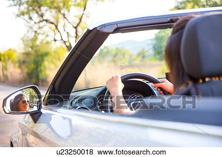 Wing mirror view of young woman driving on rural road in convertible, Majorca, Spain View Large Photo Image Stock Photo - Wing mirror view of young woman driving on rural road in convertible, Majorca, Spain. Fotosearch