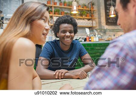 Woman and male friends chatting together in cafe View Large Photo Image Stock Image - Woman and male friends chatting together in cafe. Fotosearch