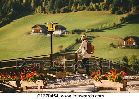 Picture - Woman enjoying view by wooden fence, Santa Maddalena, Dolomite Alps, Val di Funes (Funes Valley), South Tyrol, Italy. Fotosearch