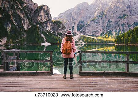 Stock Image - Woman enjoying view on pier, Lago di Braies, Dolomite Alps, Val di Braies, South Tyrol, Italy. Fotosearch