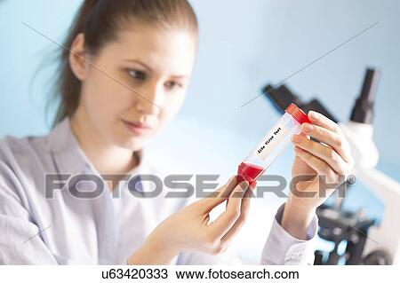 Stock Image - Woman holding blood sample in test tube. Fotosearch