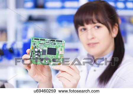 Stock Photo - Woman holding circuit board, portrait. Fotosearch