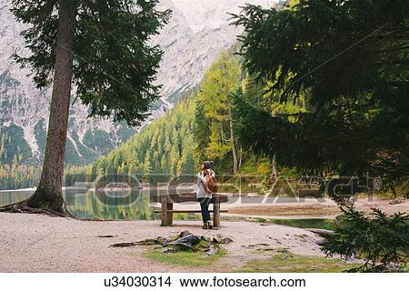Picture - Woman leaning against park bench, Lago di Braies, Dolomite Alps, Val di Braies, South Tyrol, Italy. Fotosearch
