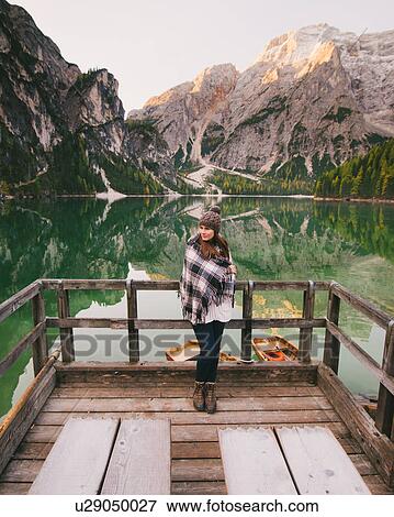 Stock Photo - Woman leaning against wooden railings, Lago di Braies, Dolomite Alps, Val di Braies, South Tyrol, Italy. Fotosearch