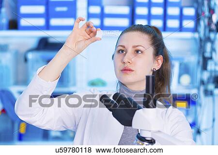 Stock Photo - Woman looking at microscope slide. Fotosearch