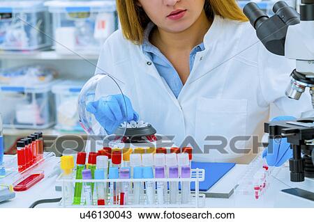 Stock Image - Woman putting micro tubes in centrifuge. Fotosearch