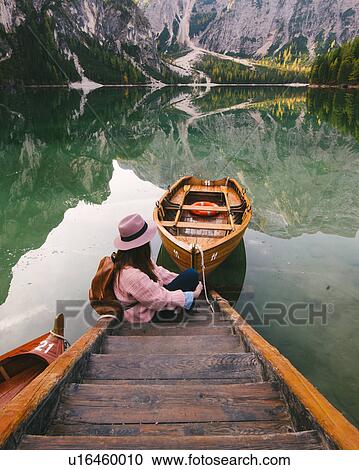 Stock Image - Woman relaxing on pier, Lago di Braies, Dolomite Alps, Val di Braies, South Tyrol, Italy. Fotosearch