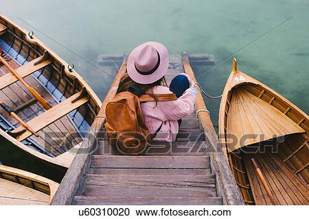 Stock Image - Woman relaxing on pier, Lago di Braies, Dolomite Alps, Val di Braies, South Tyrol, Italy. Fotosearch